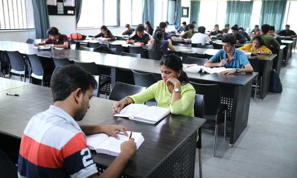 Students studying in a modern, quiet library with spacious seating and ample natural light.